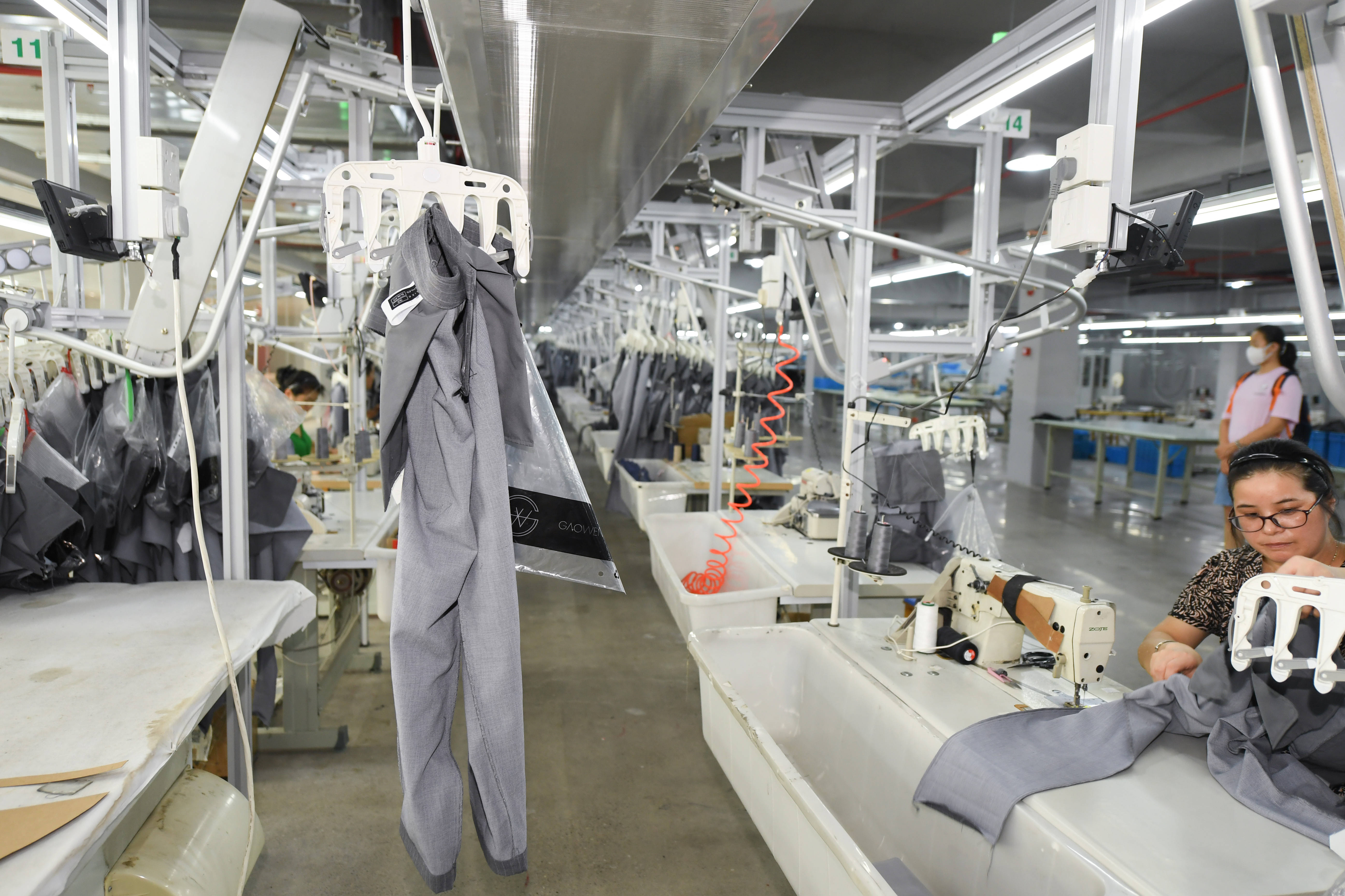 在浙江巴鲁特服饰股份有限公司的生产车间,工作人员在加装了智能吊挂